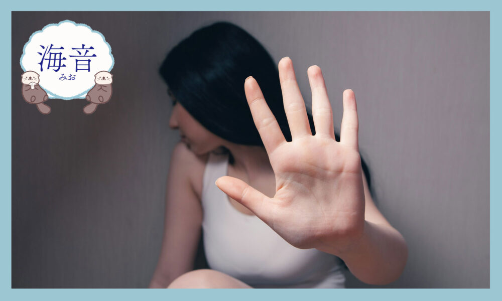 白いタンクトップ姿で手で顔を隠す女性