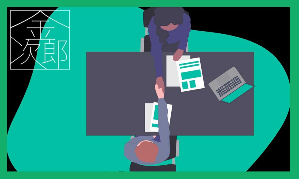 机を挟んで握手をしているビジネスマンを真上から見る