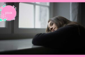 窓辺のテーブルに腕を置き、頬を預けながら外をぼんやり見つめる女性