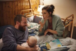 ベッドの上で、手話をつかって子どもをあやす女性と、子どもを支える男性