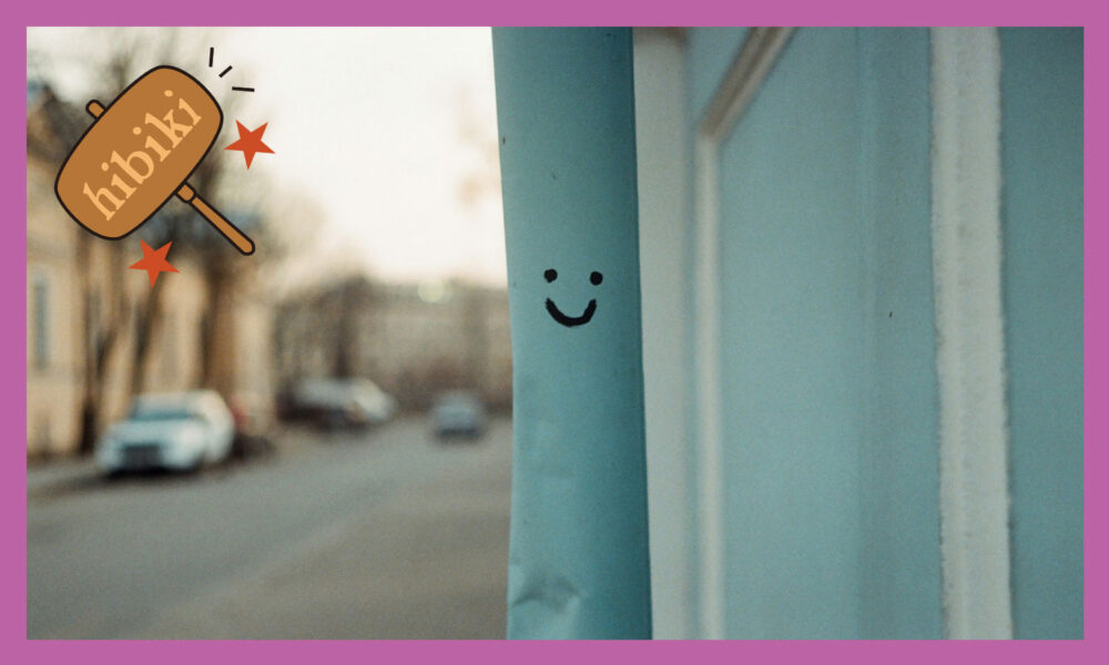 鉄パイプに黒のペンで笑っている表情が書かれている。