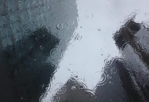 雨が降り、水たまりに映るビルの輪郭。