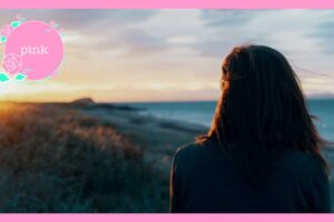 海辺で夕日を見ている女性の後ろ姿