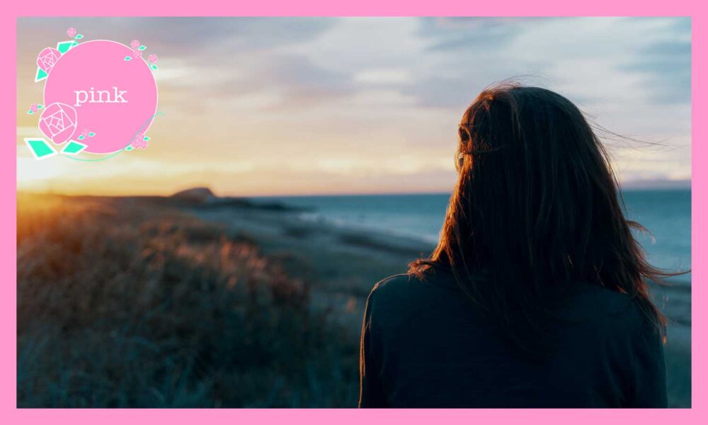 海辺で夕日を見ている女性の後ろ姿