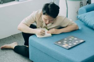 青いソファの上で、ノートにメモをとっている男性