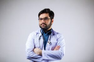 聴診器を首からかけて、腕を組み、眼鏡をかけた白衣姿の男性医師