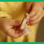 補聴器を持つ黄色い服を着た子供の手