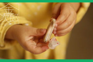 補聴器を持つ黄色い服を着た子供の手