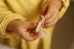 補聴器を持つ黄色い服を着た子供の手