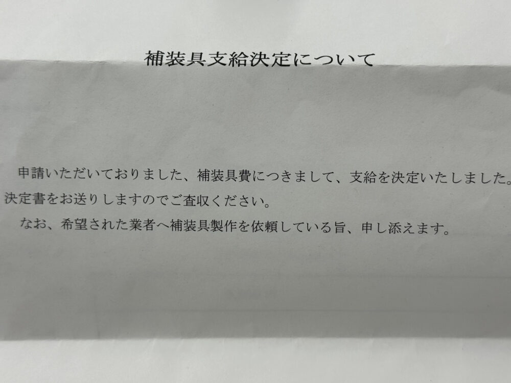 「補装具支給決定について」と題された通知書の画像。本文は「申請いただいておりました、補装具費につきまして、支給を決定いたしました。決定書をお送りしますのでご査収ください。なお、希望された業者へ補装具製作を依頼している旨、申し添えます。」と書かれている。