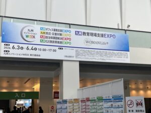 館内の大看板にイベント名が記載されている。九州イノベーションWEEK。4種類のEXPO名が記載されている。オフィス業務支援,防災・災害対策,自治体課題解決,GX脱炭素推進。