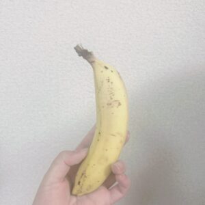 白い壁の前でバナナを持っている人の手