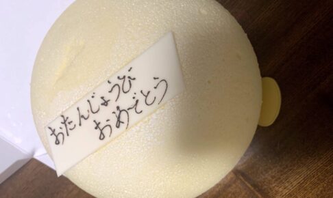 丸い白い可愛いケーキに白いチョコが乗っている。そのチョコにおたんじょうびおめでとうと書いてある。
